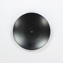 Load image into Gallery viewer, A deep black, round, metal saucer-shaped candle holder with a central hole for holding a candle.