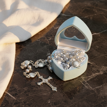 Load image into Gallery viewer, A blue rosary and a blue heart shaped box on a dark marble surface.