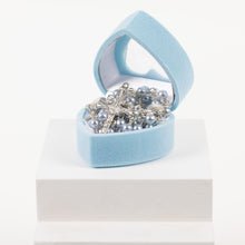 Load image into Gallery viewer, A blue heart shaped rosary box lays open displaying a blue rosary beads with a silver cross and clam shell details.